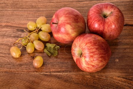 Téléchargez les photos : Pommes et raisins sur la table rustique en bois - en image libre de droit