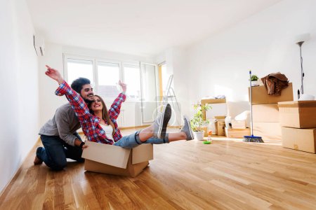 glückliches junges Paar genießt in seiner neuen leeren Wohnung