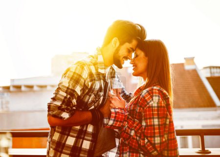 Téléchargez les photos : Jeune couple décontracté célébrant avec champagne sur la terrasse de l'appartement - en image libre de droit