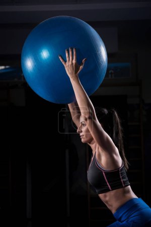 Foto de Hermosa chica de fitness celebración gimnasio bola sobre su cabeza - Imagen libre de derechos