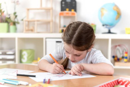 Téléchargez les photos : Mignon petite fille dessin dans la classe maternelle - en image libre de droit