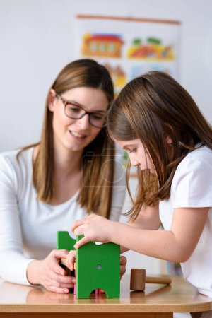 Téléchargez les photos : Professeur et enfant jouant avec des jouets didactiques colorés à l'intérieur - préscolaire - en image libre de droit