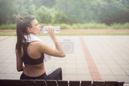 Photo for Sport Girl Sitting On The Bench, Drinking Water - Royalty Free Image