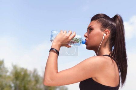 Foto de Chica trotando con auriculares y teléfono inteligente de agua potable - Imagen libre de derechos