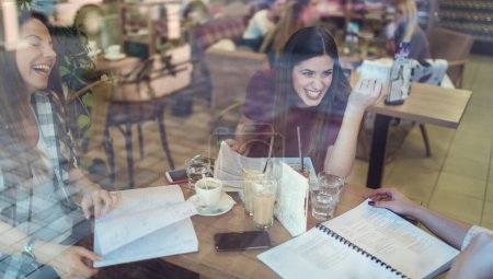 Téléchargez les photos : Souriant étudiants filles parler dans café-restaurant après les cours - en image libre de droit