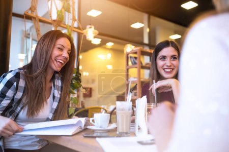 Téléchargez les photos : Souriant étudiants filles parler dans café-restaurant après les cours - en image libre de droit