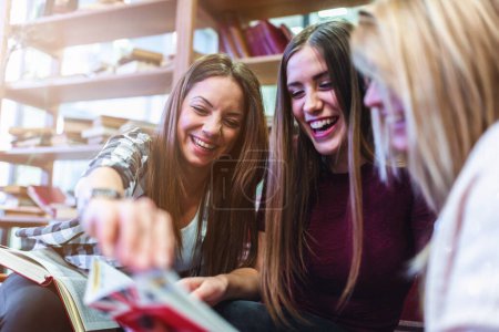 Photo for Group of young female college students studying together in library - Royalty Free Image