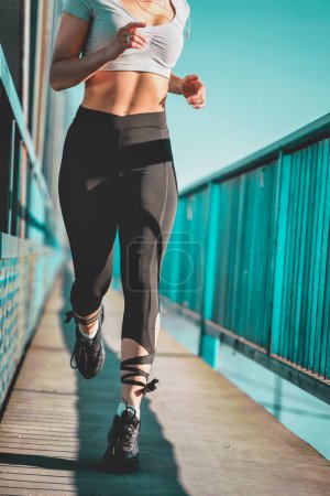 Téléchargez les photos : Jeune femme coureuse en legging courant sur le pont de la ville - en image libre de droit
