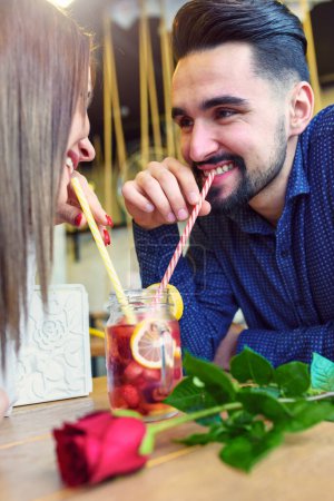 Téléchargez les photos : Jeune couple d'amour au café, Boire dans le même verre avec des pailles - en image libre de droit
