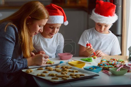 Téléchargez les photos : Mère avec des enfants faisant des biscuits pour Noël - en image libre de droit