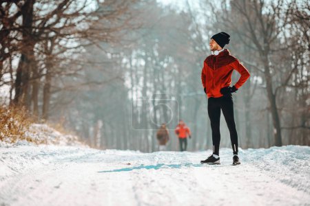 Téléchargez les photos : Homme sportif prenant une pause de la course dans des conditions de neige extrêmes - en image libre de droit
