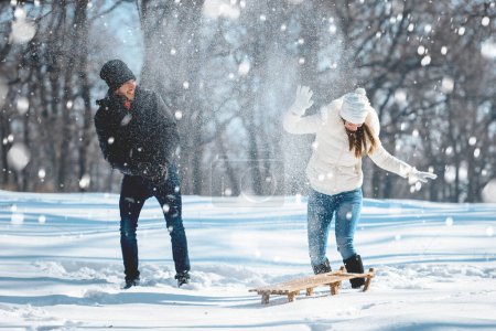 Téléchargez les photos : Jeune couple jouant avec la neige sur la forêt d'hiver - en image libre de droit