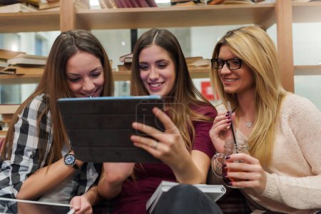 Téléchargez les photos : Couple d'étudiantes regardant tablette à la cafétéria de l'école - en image libre de droit