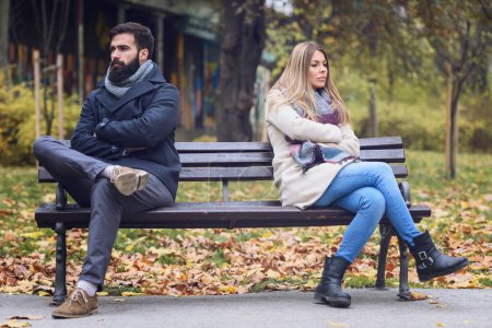 Téléchargez les photos : Couple assis dans le parc ayant des problèmes relationnels - en image libre de droit
