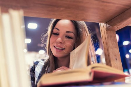 Téléchargez les photos : Femme lisant des livres à la bibliothèque - en image libre de droit