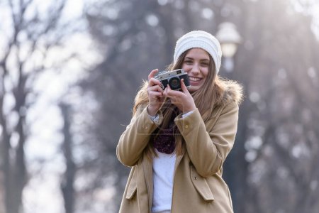Photo for Portrait of winter girl taking photo with vintage camera - Royalty Free Image
