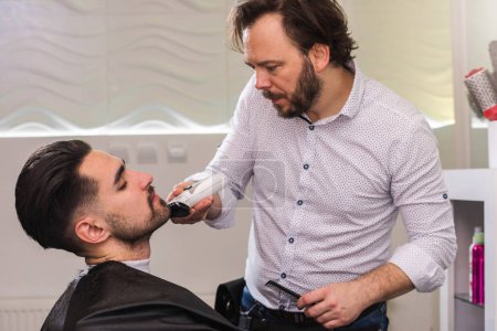Téléchargez les photos : Homme ayant sa barbe taillée dans le salon de coiffure - en image libre de droit