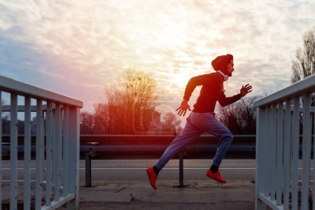 Photo for Active jogger man running by the road in the sunset - Royalty Free Image