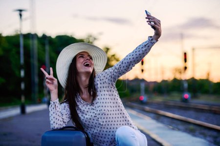 Téléchargez les photos : Jeune femme souriante faisant selfie en utilisant un smartphone - en image libre de droit