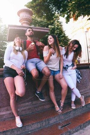Foto de Grupo de amigos divirtiéndose junto a la fuente pública en el día de verano - Imagen libre de derechos