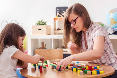 Téléchargez les photos : Mère regardant son enfant jouer avec des blocs de construction de jouets - en image libre de droit