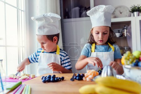 Photo for Kid chefs in the kitchen - preparing a healthy fruit snack. Activities for kids. - Royalty Free Image