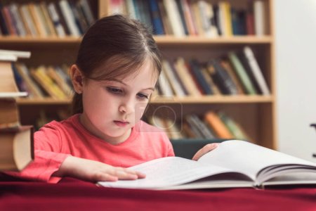 Téléchargez les photos : Petite fille lecture livre dans la bibliothèque - en image libre de droit