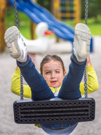 Photo for Happy child on the swing in the playground - Royalty Free Image