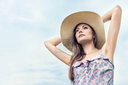 Téléchargez les photos : Belle femme en paille chapeau posant dans une journée d'été. - en image libre de droit