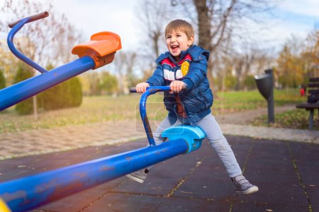 Téléchargez les photos : Heureux garçon jouer à aire de jeux dans le parc - en image libre de droit