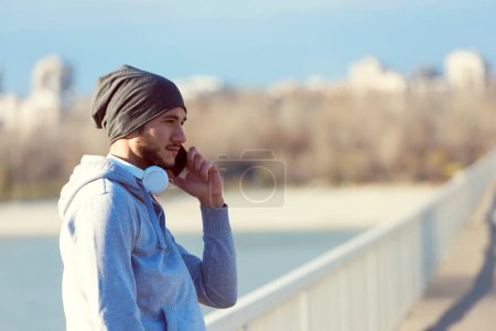 Photo for Man runner taking a break after intensive training outdoors, listening music on his mobile - Royalty Free Image