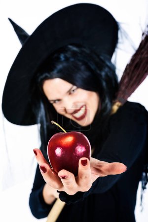 Photo for Beautiful Witch Holding Poisoned Red Apple - Royalty Free Image