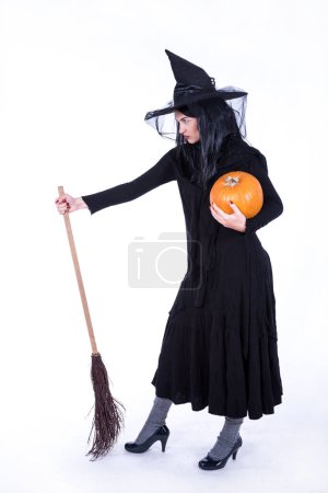 Foto de Hermosa joven bruja en traje de halloween negro celebración de calabaza - Imagen libre de derechos