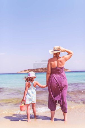 Photo for Rear view of a mother and daughter standing on perfect emerald beach - Royalty Free Image
