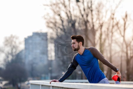 Photo for Urban Man Jogger Stretching Leg Outdoors Before Running - Royalty Free Image