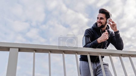 Photo for Man Jogger With Headphones Using Smartphone and Listening Music - Royalty Free Image
