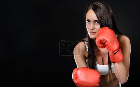 Foto de Mujer joven con guantes de boxeo rojos sobre fondo negro - Imagen libre de derechos