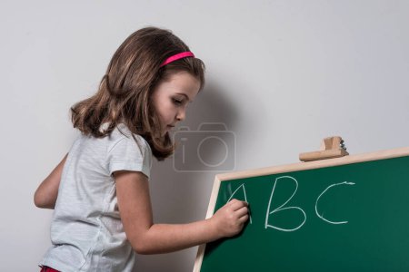 Photo for School Girl Writing on Chalkboard - Learning Letters - Royalty Free Image