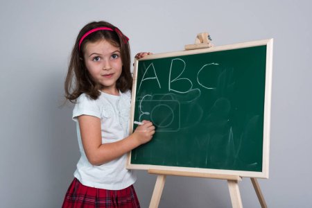 Photo for Happy School Girl in front of the Green Chalk Board - Royalty Free Image