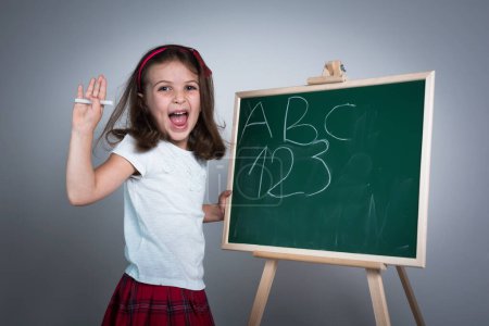 Téléchargez les photos : Happy School Girl devant le panneau de craie verte - en image libre de droit