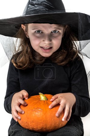 Téléchargez les photos : Petite fille en costume de sorcière tenant citrouille halloween - en image libre de droit