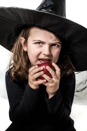 Foto de Niña con traje de bruja sosteniendo manzana envenenada roja - Imagen libre de derechos
