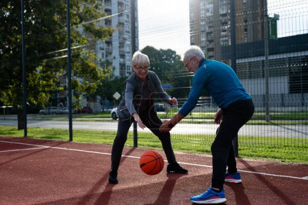 Foto de Mujer mayor y hombre maduro jugando baloncesto en el parque - Imagen libre de derechos