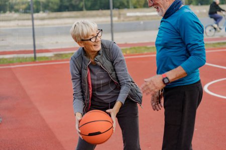 Photo for Senior woman and mature man playing basketball in the park - Royalty Free Image