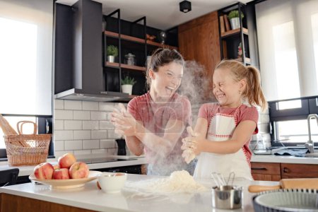 Photo for Happy mother and daughter having fun with flour together at home - Royalty Free Image