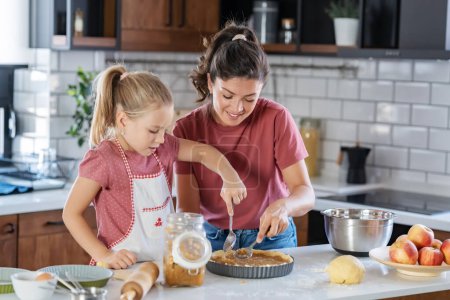 Foto de Feliz madre e hija preparando pastel juntos en la cocina - Imagen libre de derechos