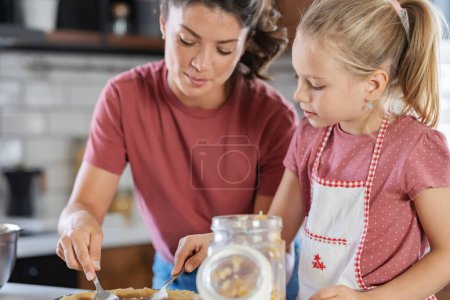 Foto de Feliz madre e hija preparando pastel juntos en la cocina - Imagen libre de derechos