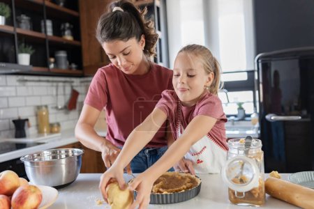Photo for Happy mother and daughter preparing pie together in kitchen - Royalty Free Image