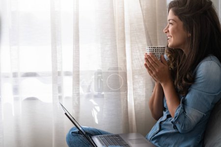 Foto de Feliz joven mujer de negocios independiente sentada en el suelo en casa trabajando en una computadora portátil - Imagen libre de derechos