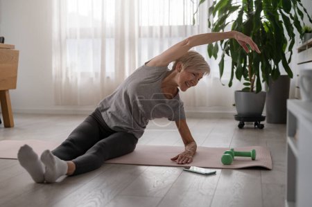Téléchargez les photos : Femme âgée active pratiquant le yoga à l'intérieur - en image libre de droit